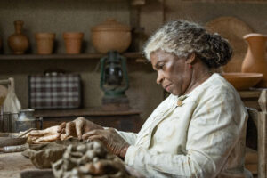Dona Menina (Zezé Motta) trabalha na roda de oleiro, enquanto Vitalino (Levi Asaf) mostra uma imagem de São Benedito. Tonho (Ronald Sotto) chega tenso para conversar com Dona Menina.